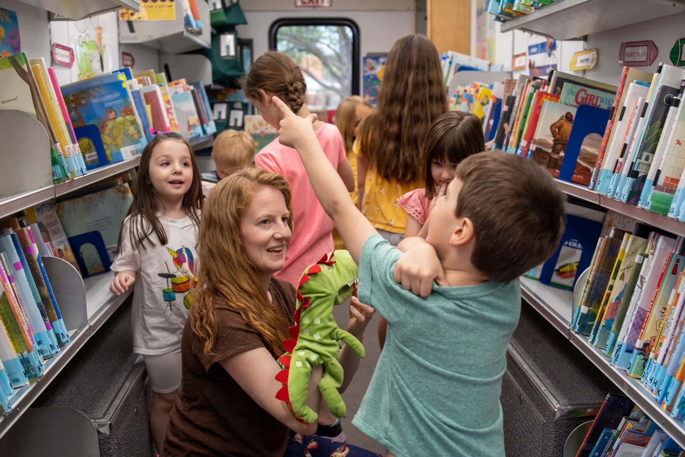 Children with Librarian on the Early Literacy bus looking at books.