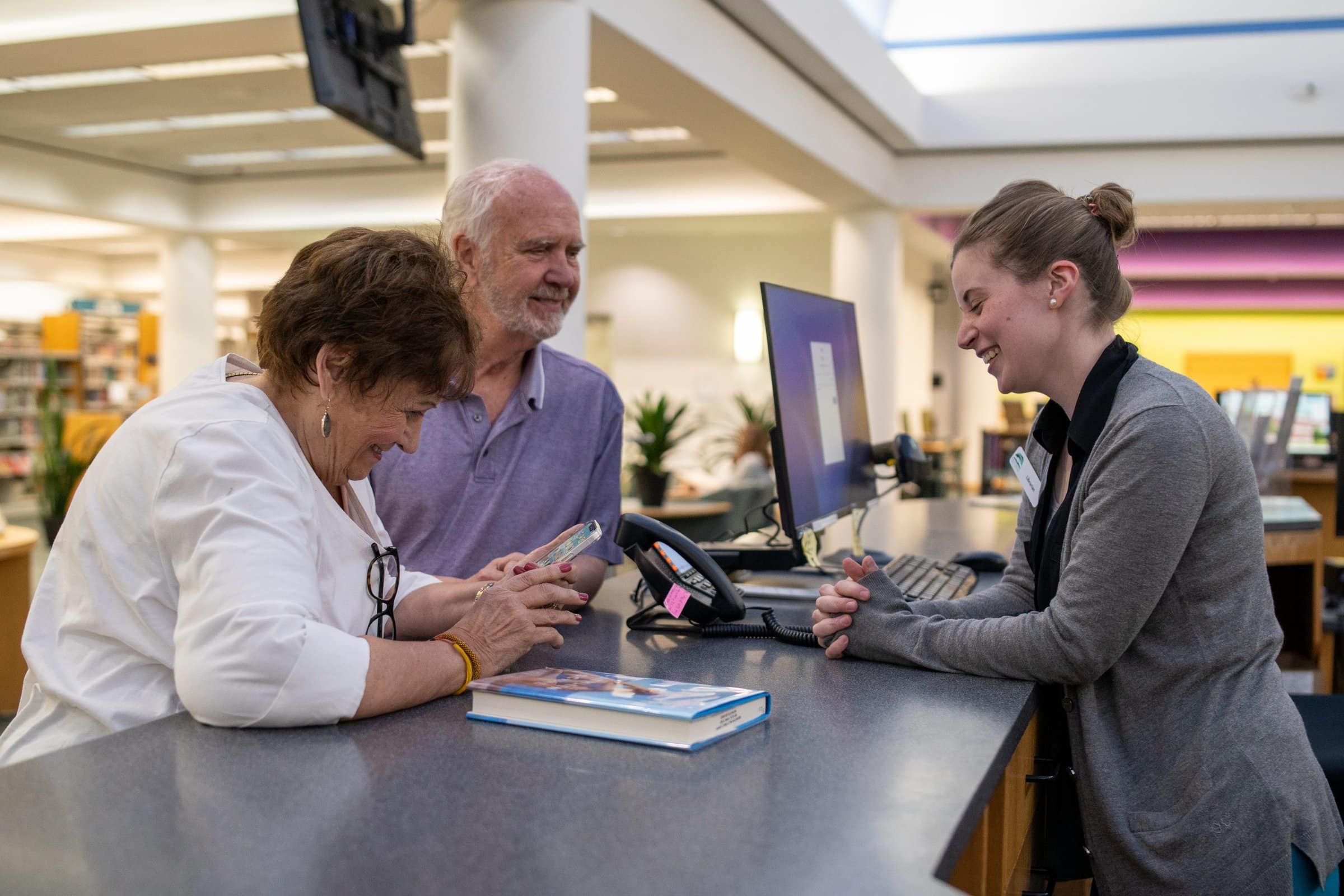 Librarian helping an elderly couple with technology